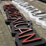 Placing letters on custom wood signage for a Mexican restaurant